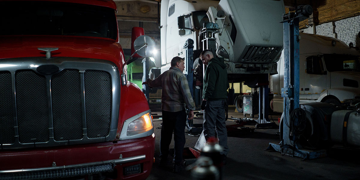 Men standing next to trucks in mechanics workshop