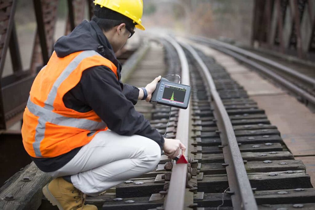 Non-destructive testing operator apprentice using testing equipment to survey the safety of train tracks
