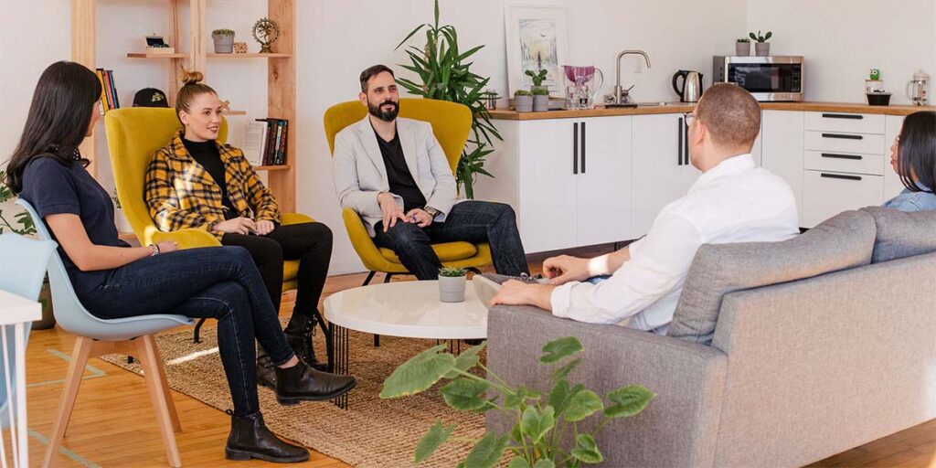 A recruitment consultant is sat on sofas with their clients