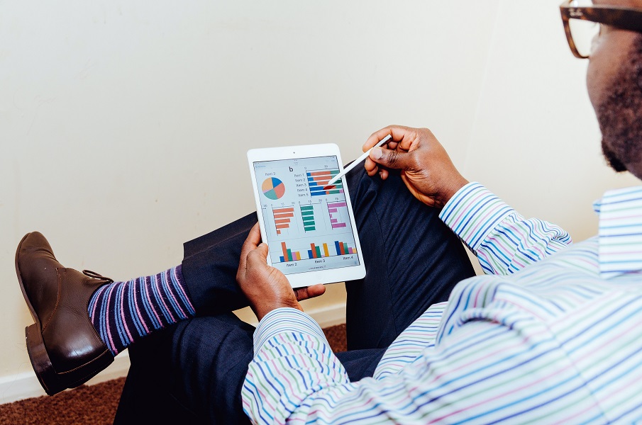 Man holding a tablet which shows graphs and charts on the screen