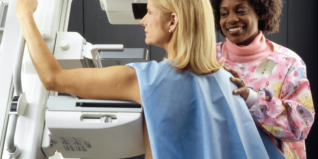 Mammography associate performing a mammogram on patient