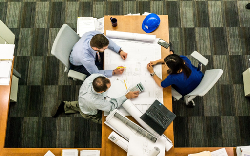 Three professionally dressed people working together at a desk