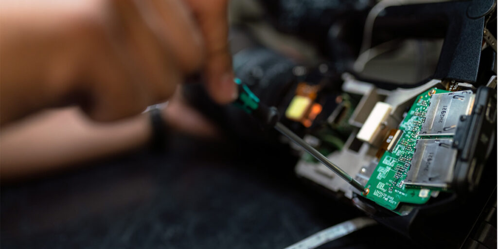 Person fixing green and black circuit board