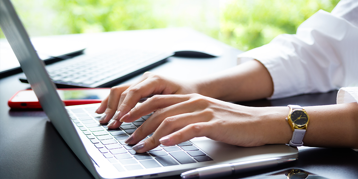 Hands typing on a laptop