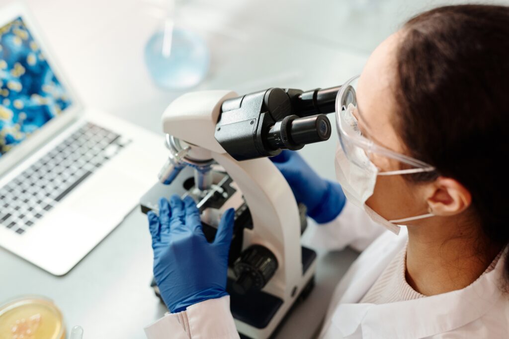 A female scientist in a laboratory looks through a microscope.