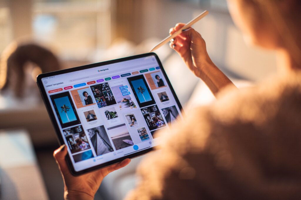 A female using Pinterest on her iPad. She is scrolling through with her apple pencil. The background is blurred.