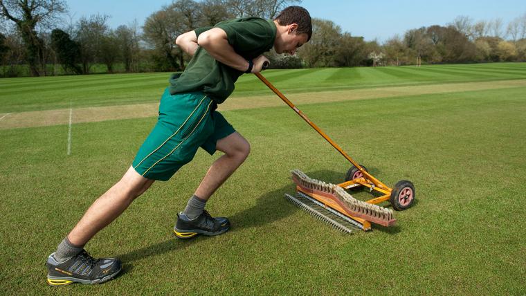 man pushing equipment on a sports turf