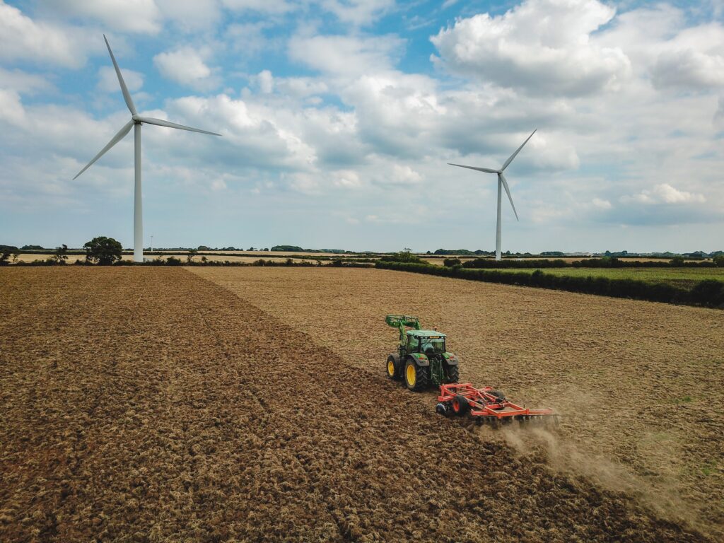 Image shows a tractor farming with a ploughing attachment in a field