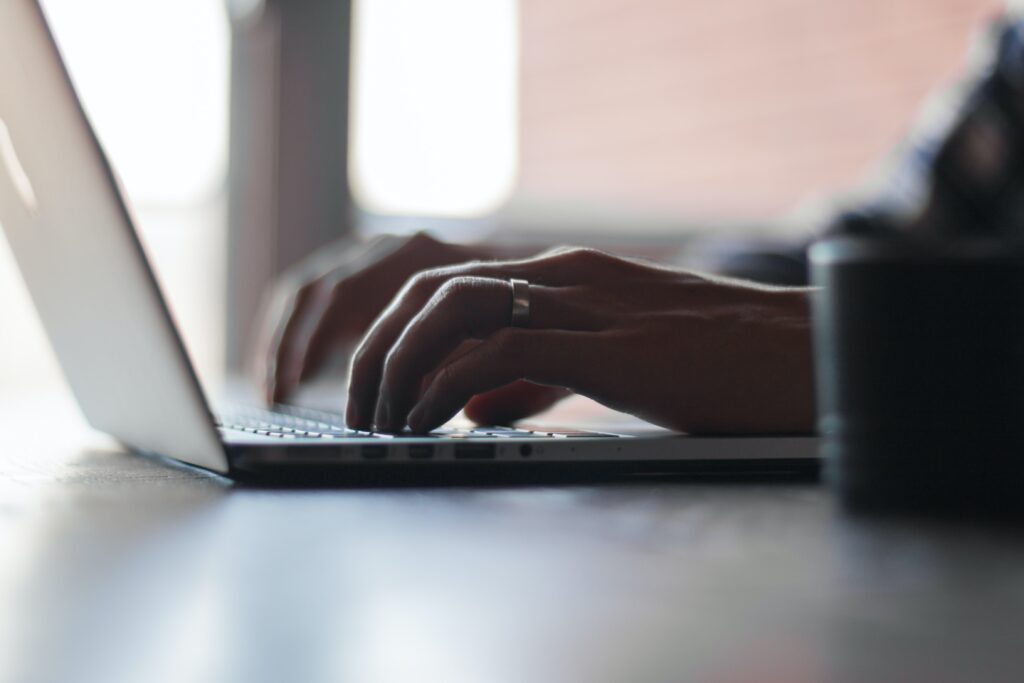Two hands typing on a laptop keyboard, completing apprenticeship work.