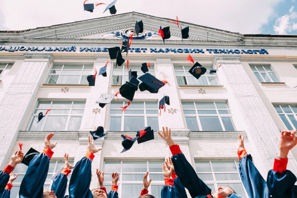 Graduating class of students throwing their caps in the air together. A key component of degree apprenticeships.